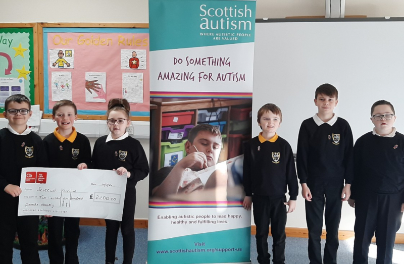 Six children smile while holding a giant cheque for Scottish Autism