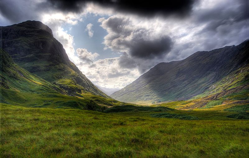 Scottish Highland landscape of Glencoe valley with sun shining through dark clouds